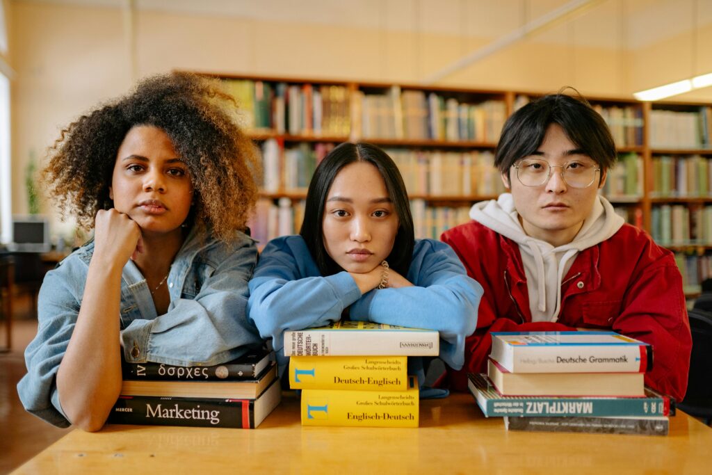 A group of diverse students engaging in studies at a library, surrounded by books and resources.